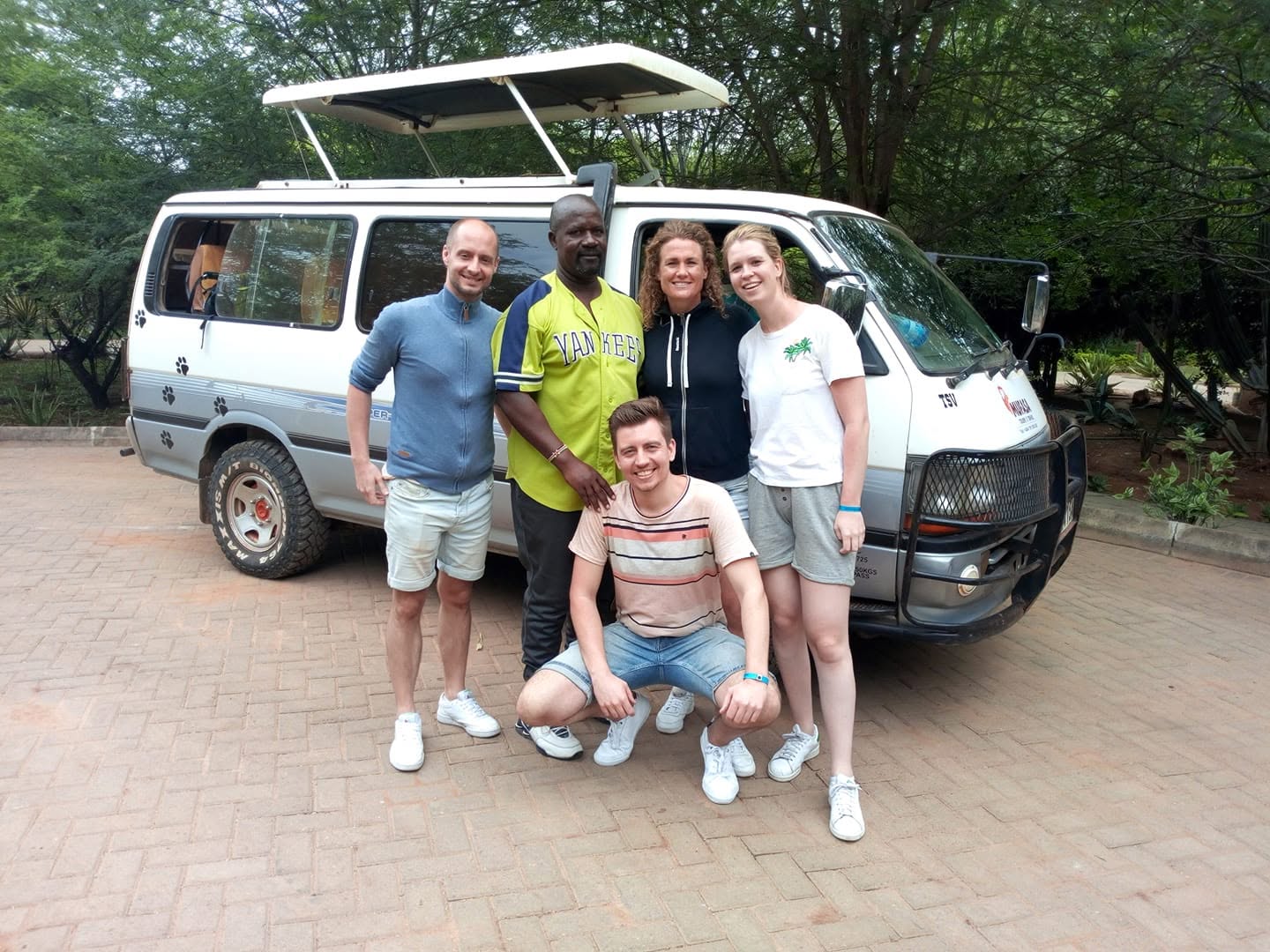 Safari guests beside safari vehicle